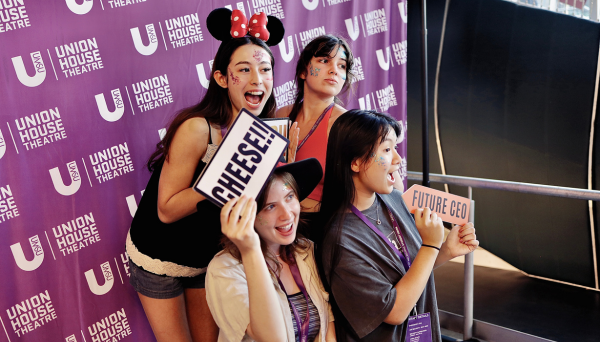Four girls posing in front of "Union House Theatre' media wall photobooth. They all are smiling.